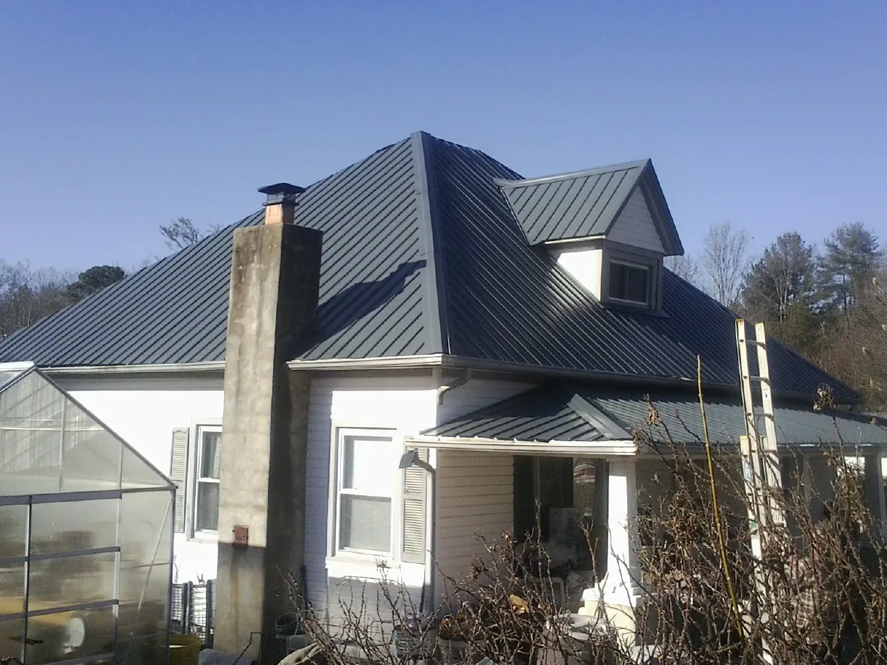Dark blue standing seam metal roof on a white farmhouse with dormer — Slate & Tile Roof Repair by Roofing Brothers in Stamping Ground