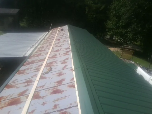 Old rusted panels beside newly installed green metal roofing — Wind Damage Roof Repair by Roofing Brothers in Stamping Ground