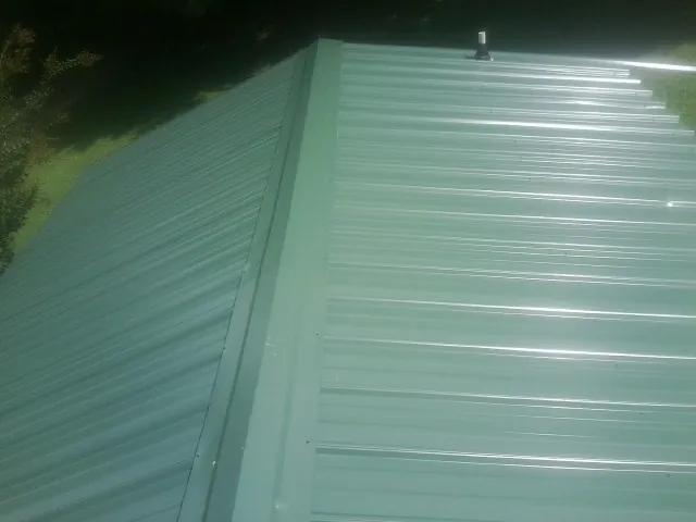 New green metal panels meeting at the ridge of a roof — Flat Roof Repair work by our crew in Stamping Ground