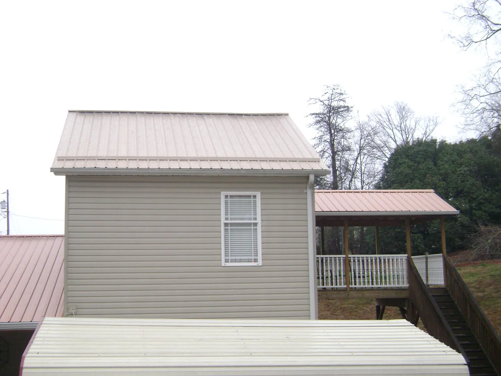 Tan metal roofs on a two story addition and attached porch, from a Roof Replacement job in Stamping Ground