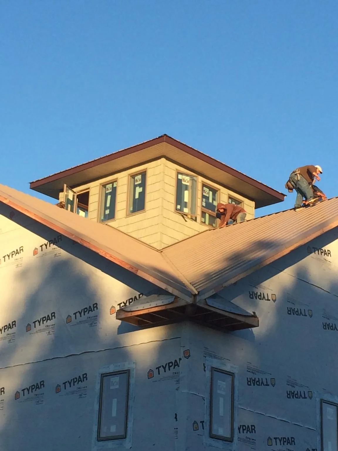 Roofers working around a rooftop cupola on a new metal roof at sunset — Roof Waterproofing in Stamping Ground by Roofing Brothers